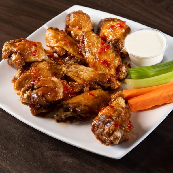 Sweet chili chicken wings with ranch, celery, and carrots on a white plate at Tukee's Sports Grille.