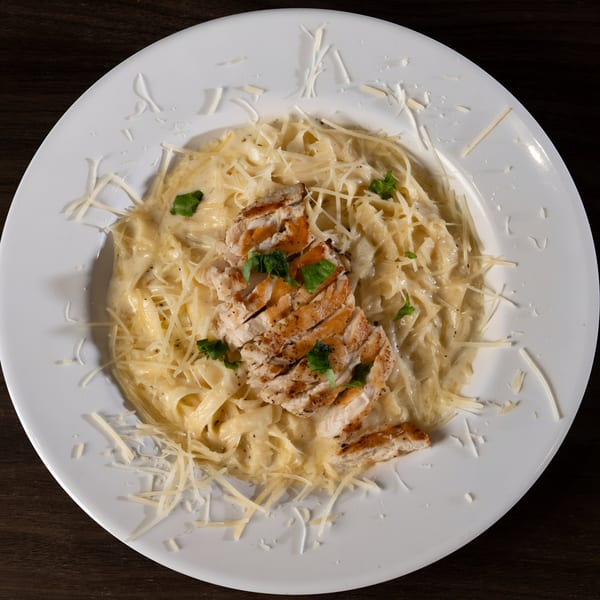 Tukee's Sports Grille's creamy fettuccine alfredo topped with sliced grilled chicken and fresh parsley.